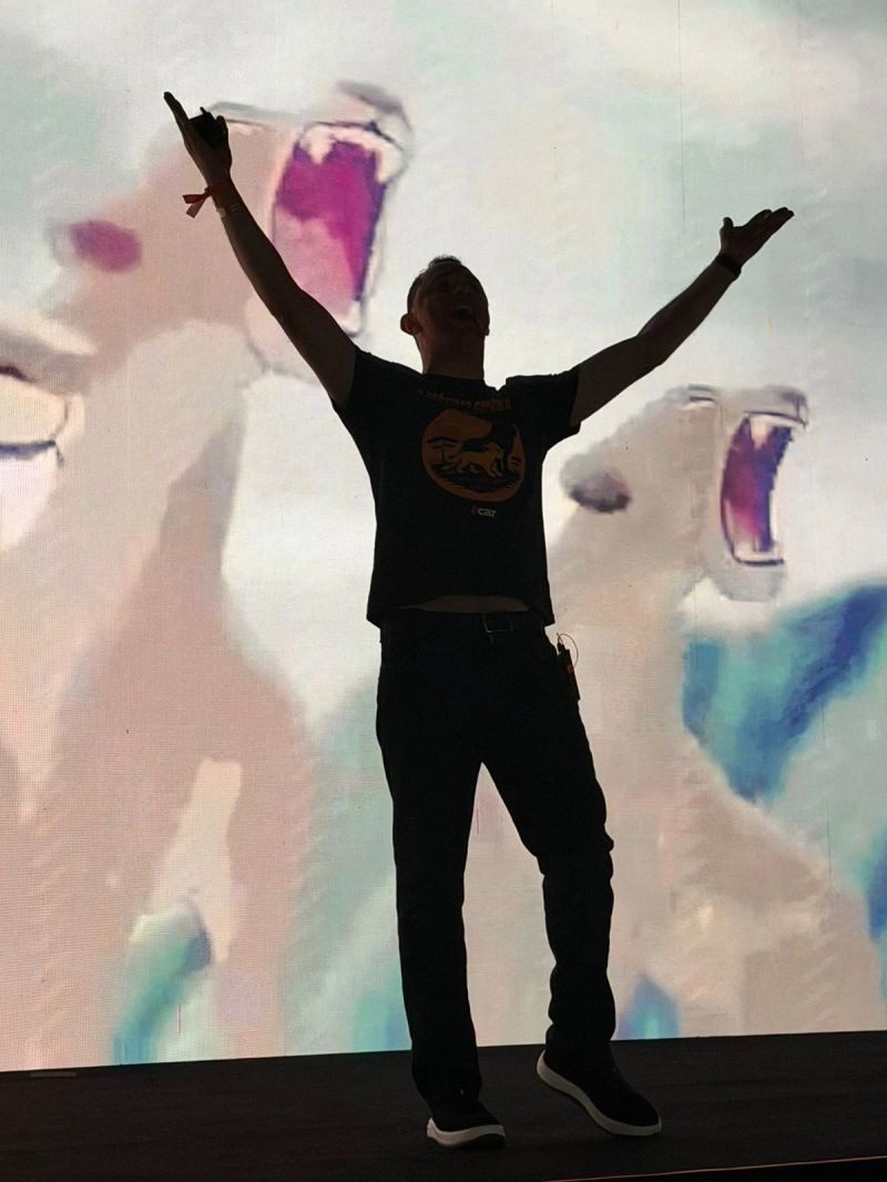 Pablo Moreno de braços abertos em silhueta contra a tela, momento de clímax da palestra